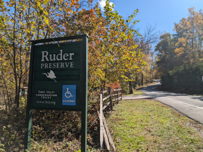 Entrance sign of Ruder Preserve on the side of road with handicap accessible symbol.