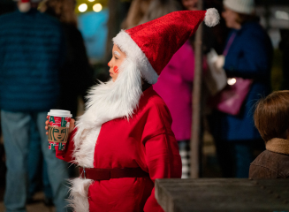 A child wearing a Santa costume holding a mug of hot cocoa