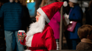 A child dressed as Santa with a beard an holding hot cocoa