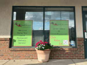 Two green window signs with Oxford to You logo outside