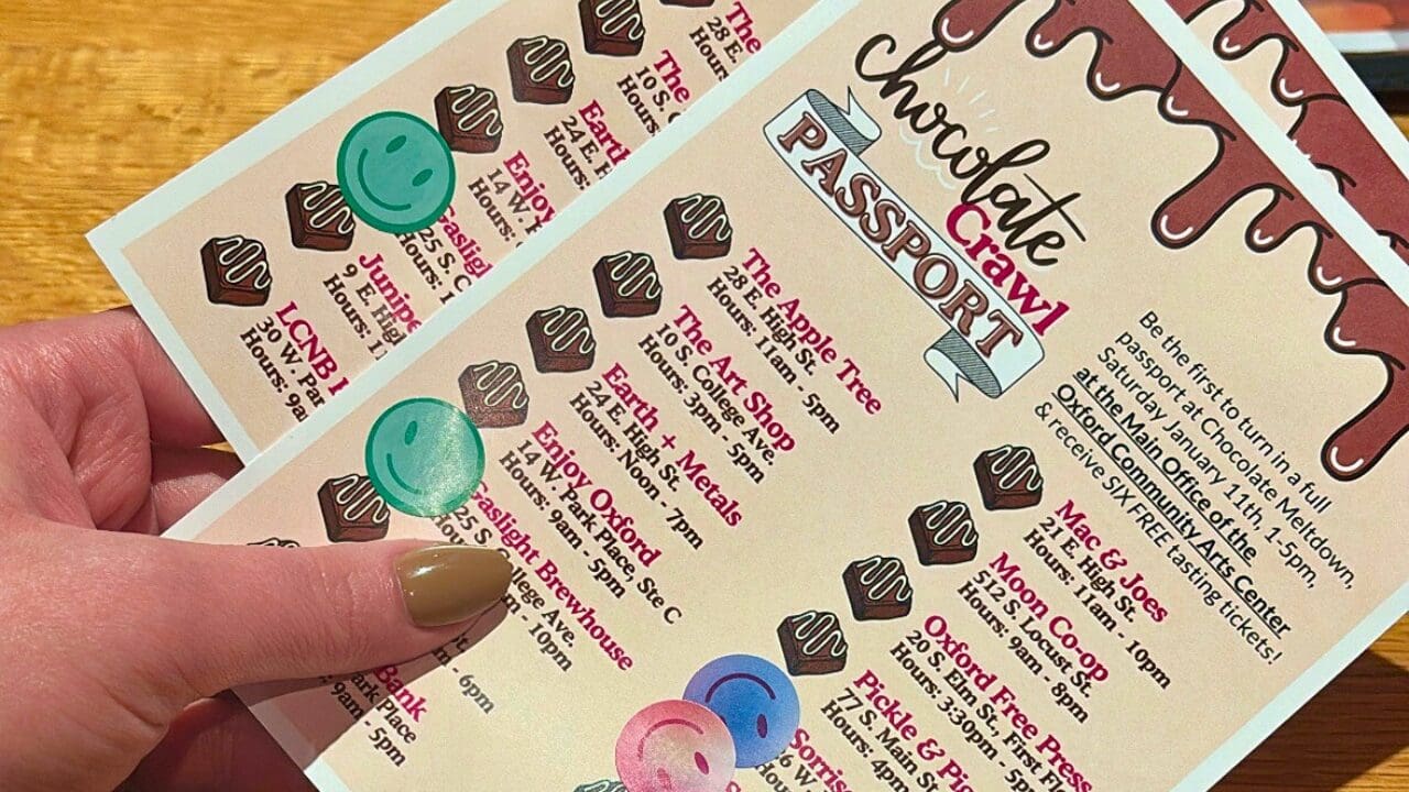 Someone holding two Chocolate Crawl Passports with locations check marked with stickers