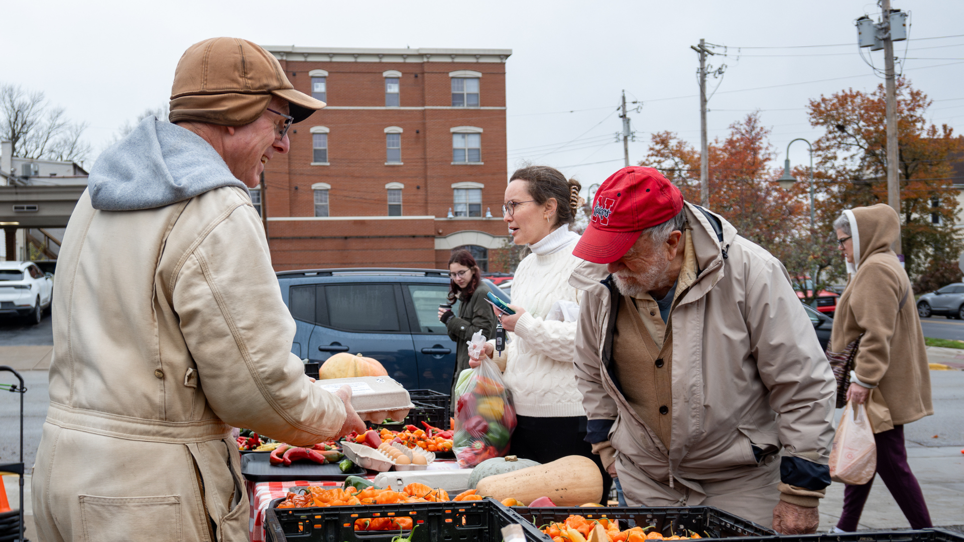 Vendor at the Oxford Farmers Market with crates of in season vegetables