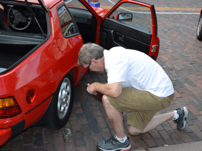 A person kneeling down looking at their car wheel