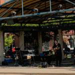 Outdoor musician performing under a pavilion stage.
