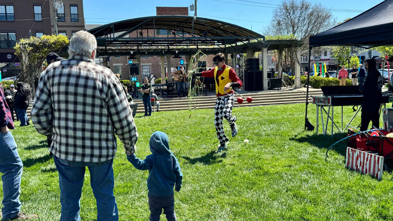 Two people holding hands watching someone on stilts at Earth Fest.