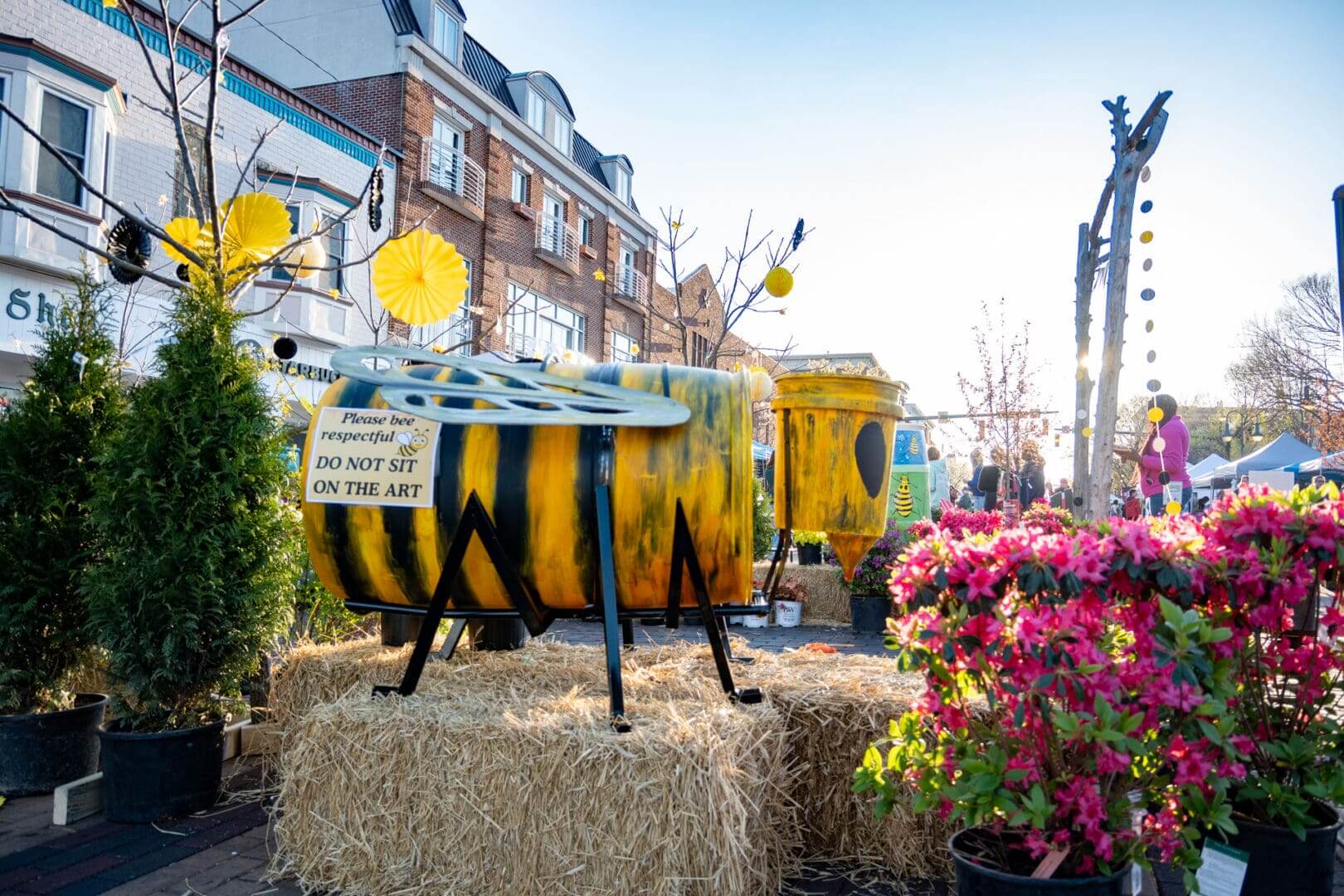 A rain barrel painted into a bee sits on top of a haystack Uptown, Oxford.