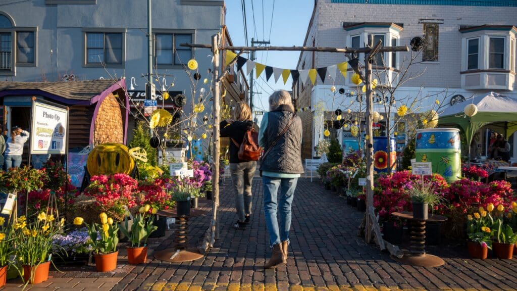 a person walking under the garden walk entrance to the Oxford Hive Mural in the alley