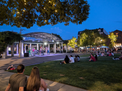 People sitting on the Oxford Memorial Park lawn in front of the pavilion at twilight