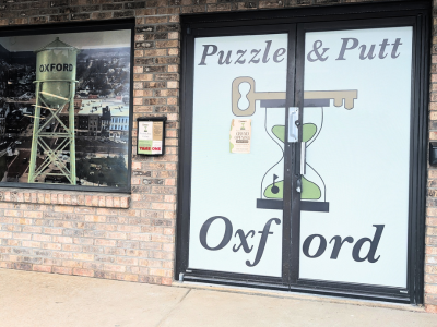 Front entrance of Puzzle & Putt Oxford with an image of a hour glass and key on the door