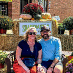 Couple sitting at pumpkin-themed fall display.