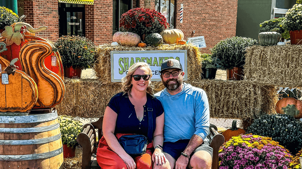 Couple sitting at pumpkin-themed fall display.