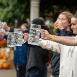 a group of people on stage holding beer steins of water to win a prize