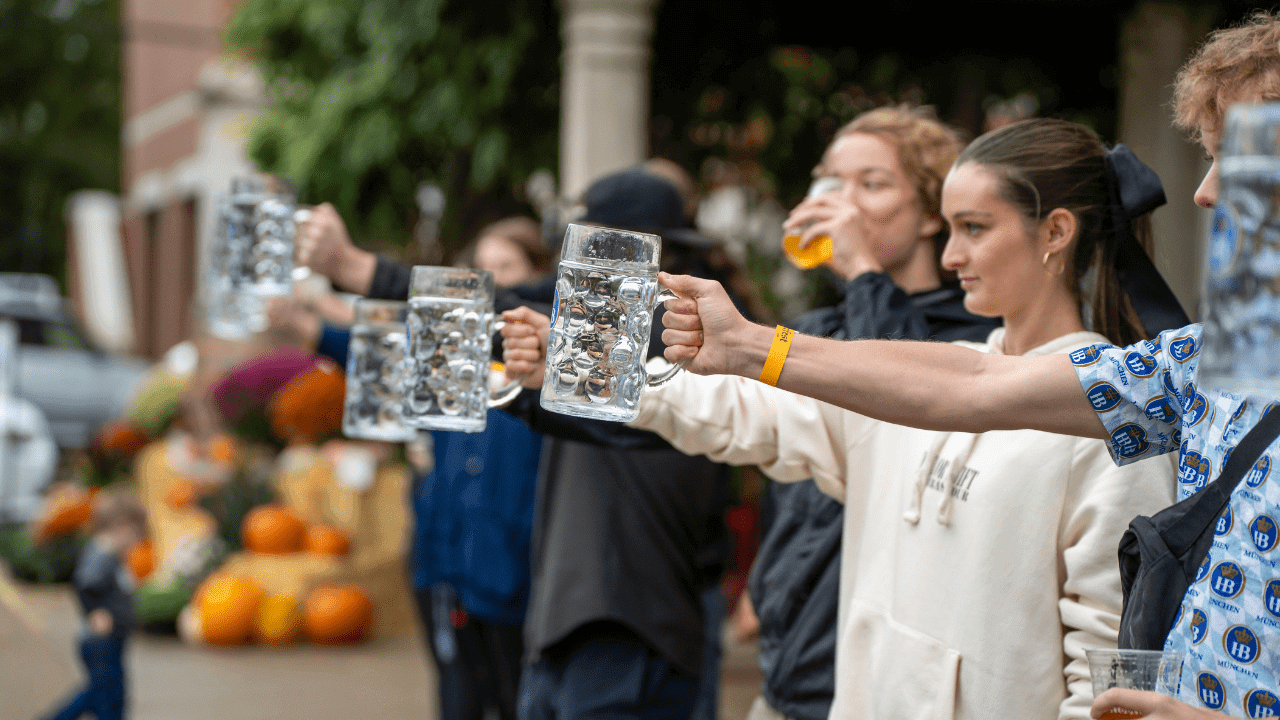 a group of people on stage holding beer steins of water to win a prize