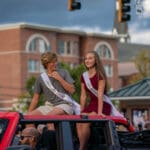 Two members of the Talawanda HS Homecoming Court ride on the back of a jeep in the parade.