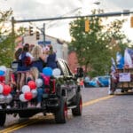 A series of trucks carries students down the red bricked streets of Uptown Oxford during the Talawanda HS Homecoming parade.