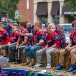 A group of younger football players sits on hay bails in the back of a truck during the Talawanda High School Homecoming parade.