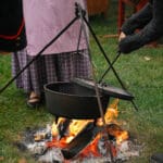 Someone using a tool to open the lid of a Dutch oven.