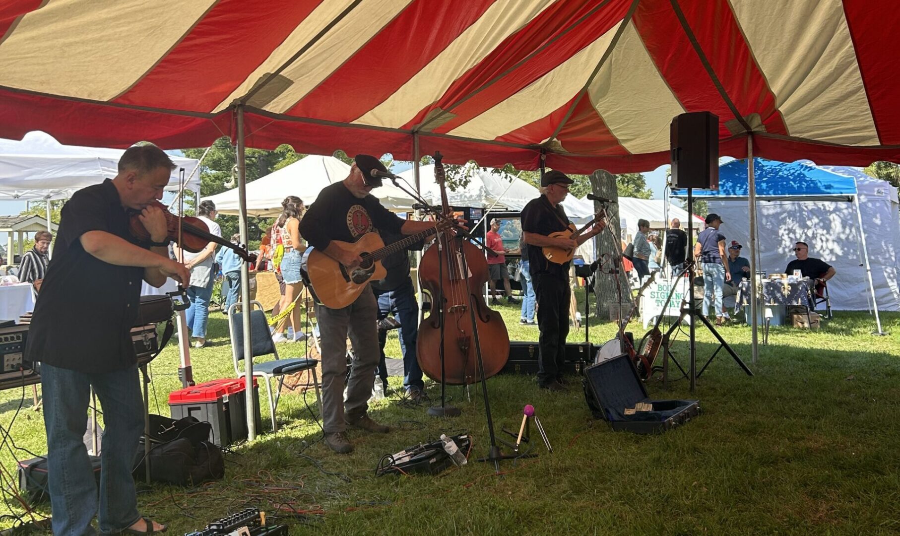 A four-piece band performs under a tent at the Apple Butter Festival.