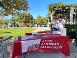 two people standing on the side of a booth that reads Asian American Association
