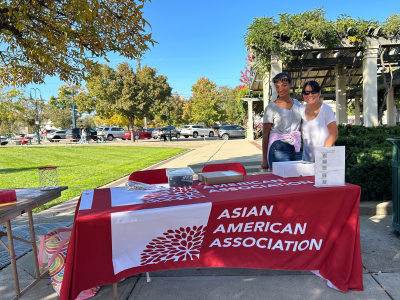 two people standing on the side of a booth that reads Asian American Association