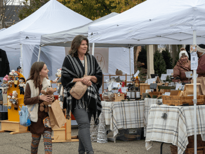 A woman and child walking with purchased items at Oxford Farm & Flea