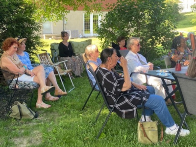 A group of people sitting in lawn chairs outside Snazzy Boutique for Open House