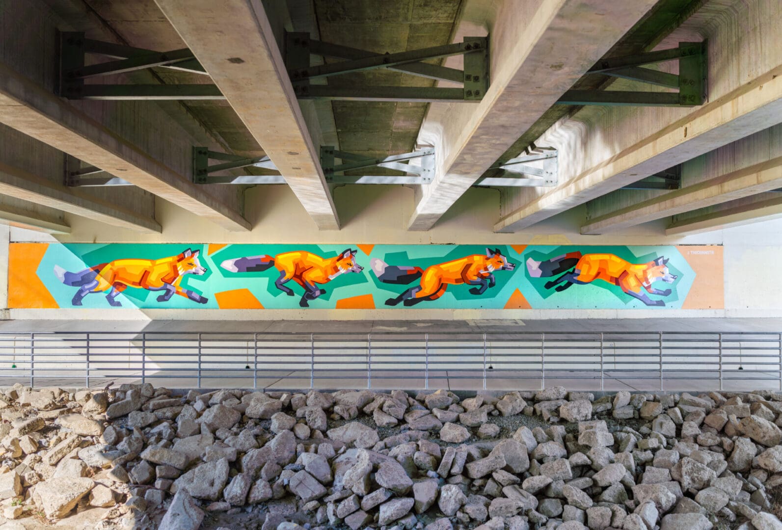 Fox mural under bridge with rocks below.