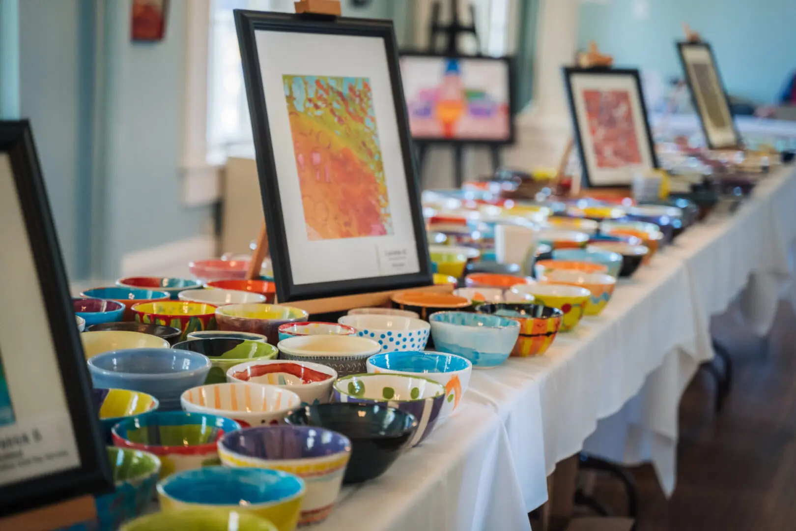 A table with rows of unique painted and hand made bowls for Oxford Empty Bowls