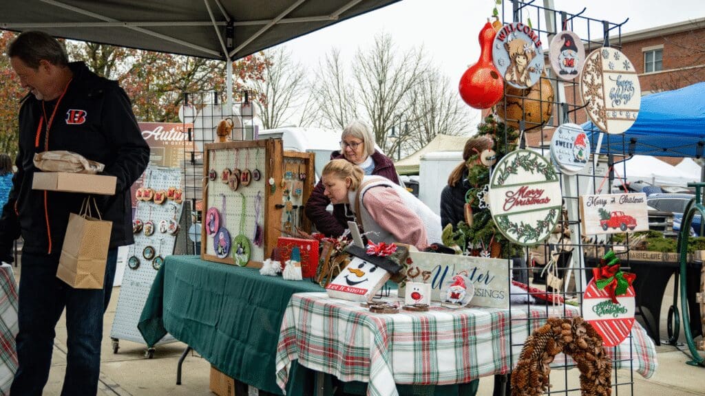 A group of people shopping at a vendor booth of holiday items