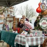 A group of people shopping at a vendor booth of holiday items