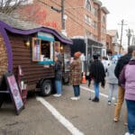 A line of people waits to purchase food from a local food truck.