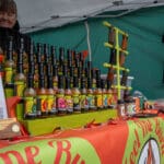 A wide variety of hot sauces is displayed on top of a table at a local vendor's booth.