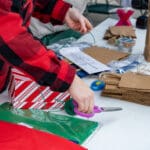 Person wrapping gifts at a table.