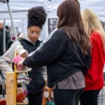 A group of people examines a display of handmade stuffed animals.