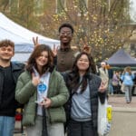 A group of young people poses in the middle of Uptown Oxford with various vendor tents in the background behind them.