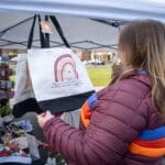 A woman examines a canvas bag that's available for sale at a vendor's booth.