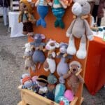 A wooden display showcases various handknit stuffed animals.
