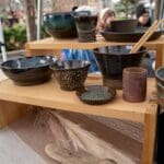 A vendor's table showcases various ceramic dishes available for purchase.
