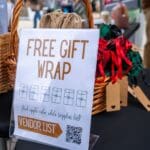 A sign that reads "Free Gift Wrap" sits on top of a table.