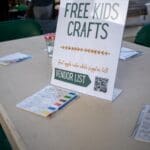 A sign that reads "Free Kids Crafts" sits on top of a table.