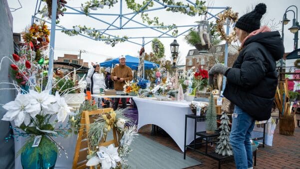 a patron looking through a vendor tent of artisan holiday goods.