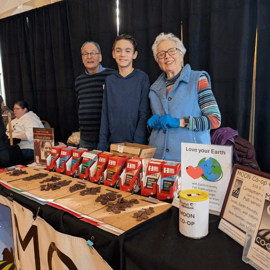three people managing the moon co-op booth with organic chocolate tastings