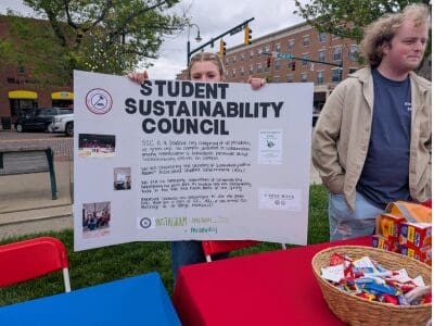 a person holding up a poster board that says "Student Sustainability Council"