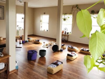 Well lit yoga studio with sets of bolsters and blanket stations set up for the next session