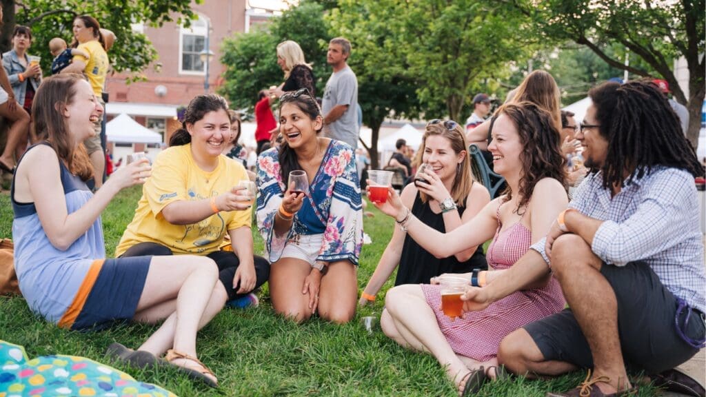 A group of people sitting on the lawn at the park drinking wine and craft beer at MLK Jr. Park