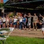 A group of people stands on the main stage while participating in a beer stein holding contest.