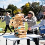 A Jenga tower topples as the players attempt to catch the falling pieces