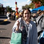 A young woman poses for the camera with a shish kabob.