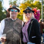 A man and woman pose for the camera, wearing German hats.