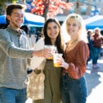 Three people cheers their beers together.